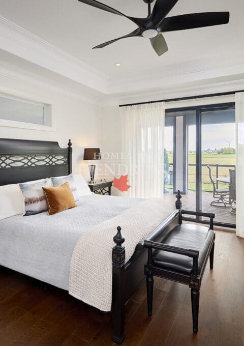 Sophisticated bedroom with black carved wood furniture, soft neutral bedding, and sliding glass doors opening to a private terrace with countryside views.