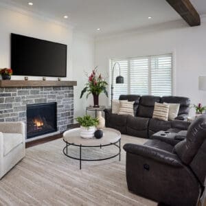 Cozy family room with stone fireplace, dark leather seating, and expansive sliding doors overlooking the backyard.