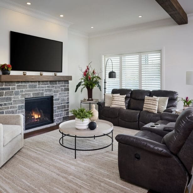Cozy family room with stone fireplace, dark leather seating, and expansive sliding doors overlooking the backyard.