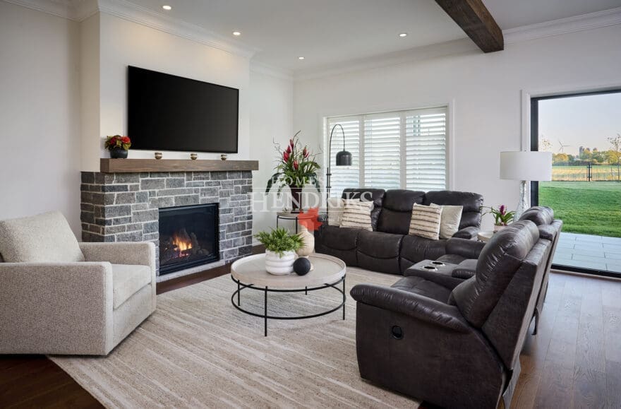 Cozy family room with stone fireplace, dark leather seating, and expansive sliding doors overlooking the backyard.
