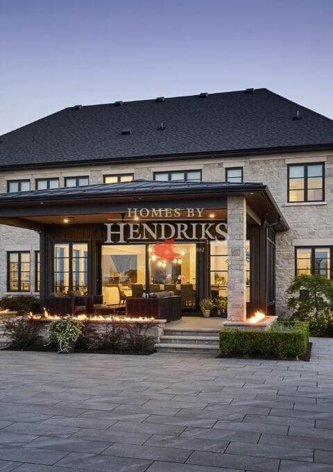 Custom-built home with a sophisticated stone façade, limestone detailing, and a serene pool and landscaped yard.