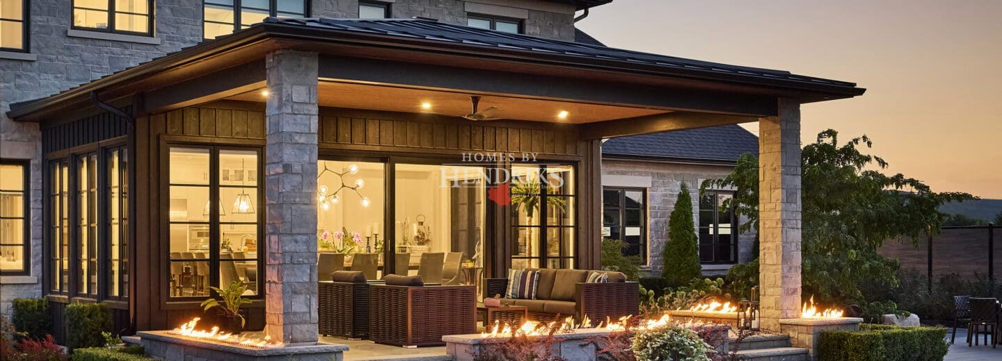 Luxurious custom home with a timeless stone exterior, accentuated by limestone and complemented by a beautiful pool and landscaped garden.