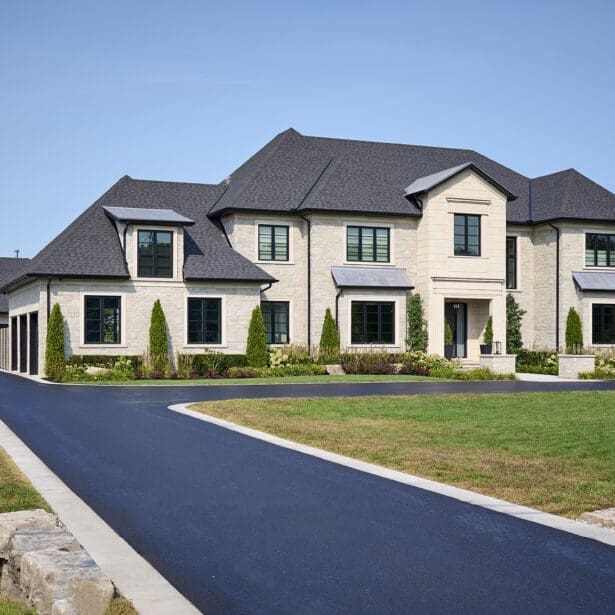 Front entry way on a custom home featuring limestone accents, paved driveway and a beautiful landscape. Chateau Style Home