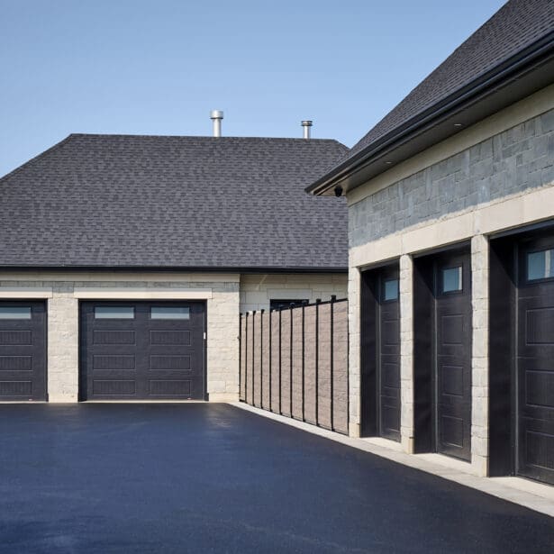 Custom luxury home with a striking stone exterior, limestone accents, and a serene backyard oasis with a pool and landscaping. Garage Doors.