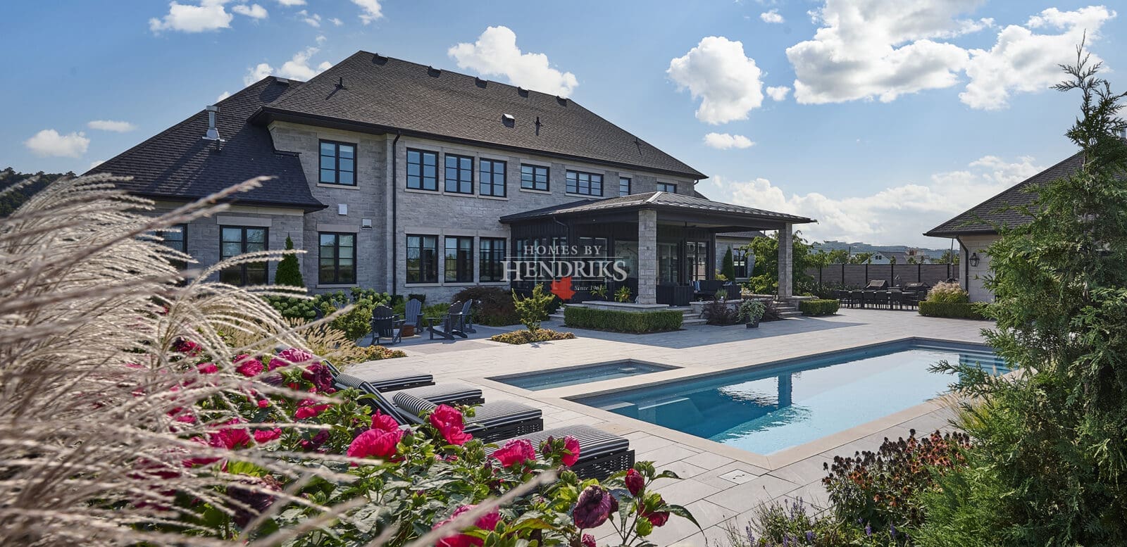 View of a modern home with an inground pool surrounded by lush landscaping.