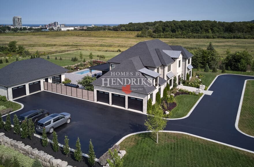 Impressive custom home with a stone exterior, limestone accents, and a beautifully landscaped yard with a sparkling pool.