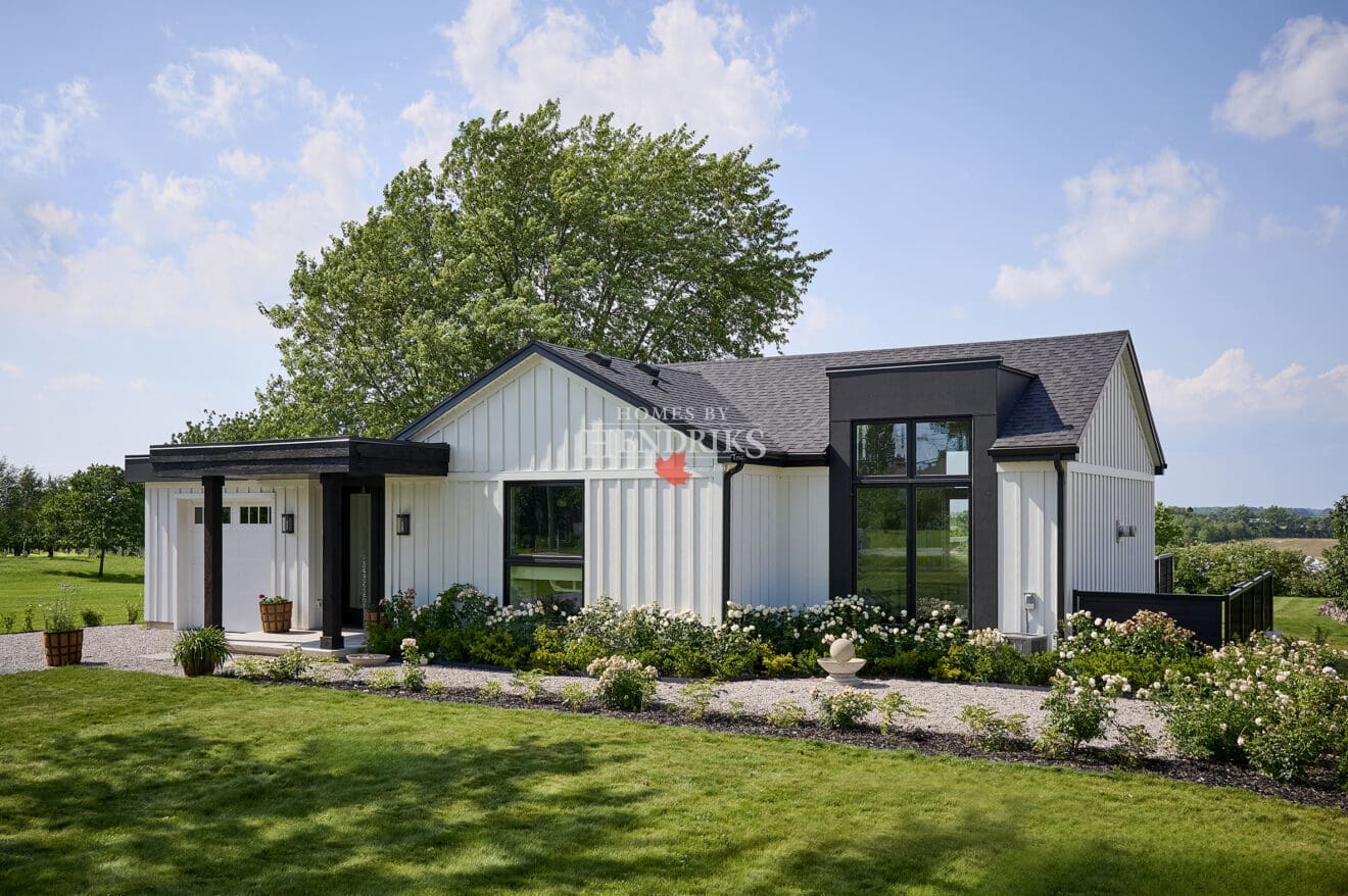 Front elevation of modern white board-and-batten custom bungalow with black accents, covered entry, and attached garage.