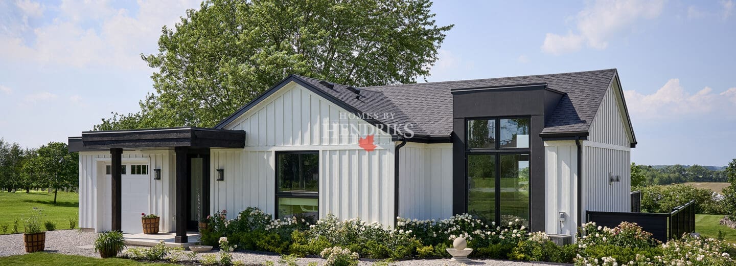 Front elevation of modern white board-and-batten custom bungalow with black accents, covered entry, and attached garage.