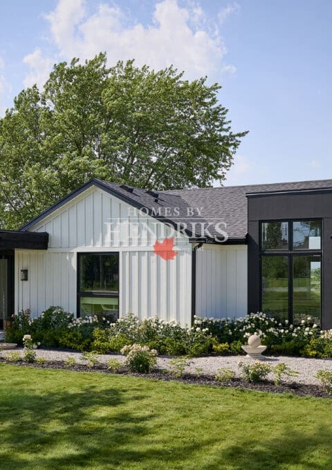 Front elevation of modern white board-and-batten custom bungalow with black accents, covered entry, and attached garage.