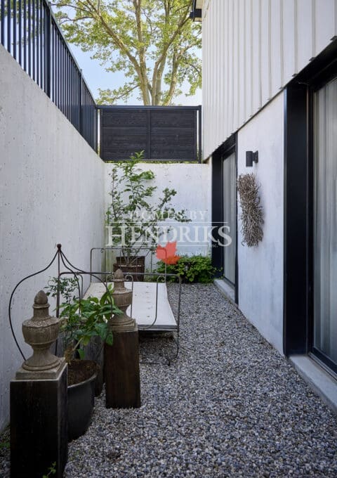 Private side courtyard with gravel walkway, modern entry door, white siding, and decorative planters.