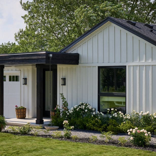 Close-up of front façade showcasing covered porch, white board-and-batten siding, black trim, and attached garage.