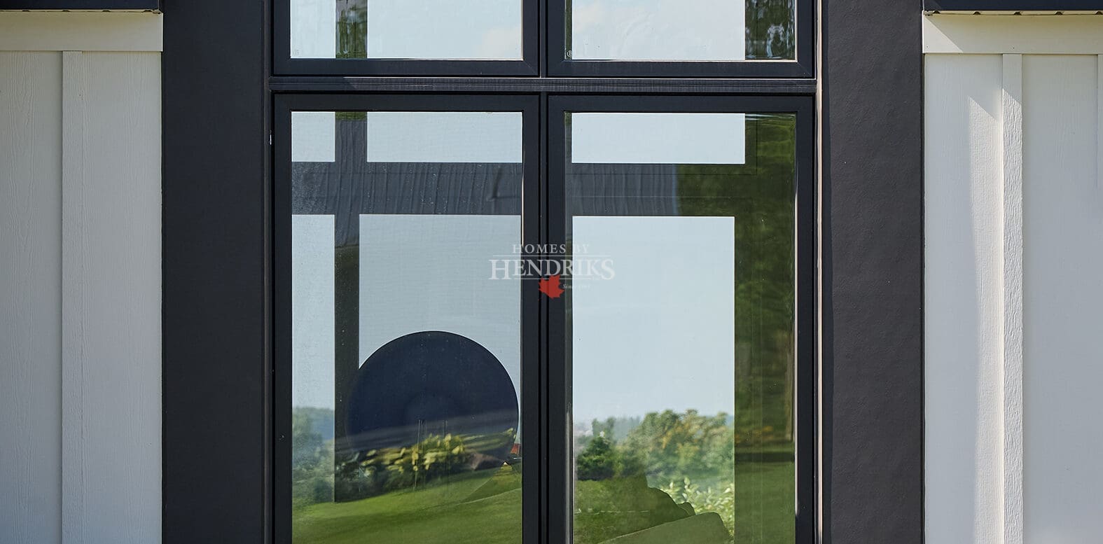 Close-up of dramatic black-framed floor-to-ceiling feature window with landscaped garden and modern exterior detailing.